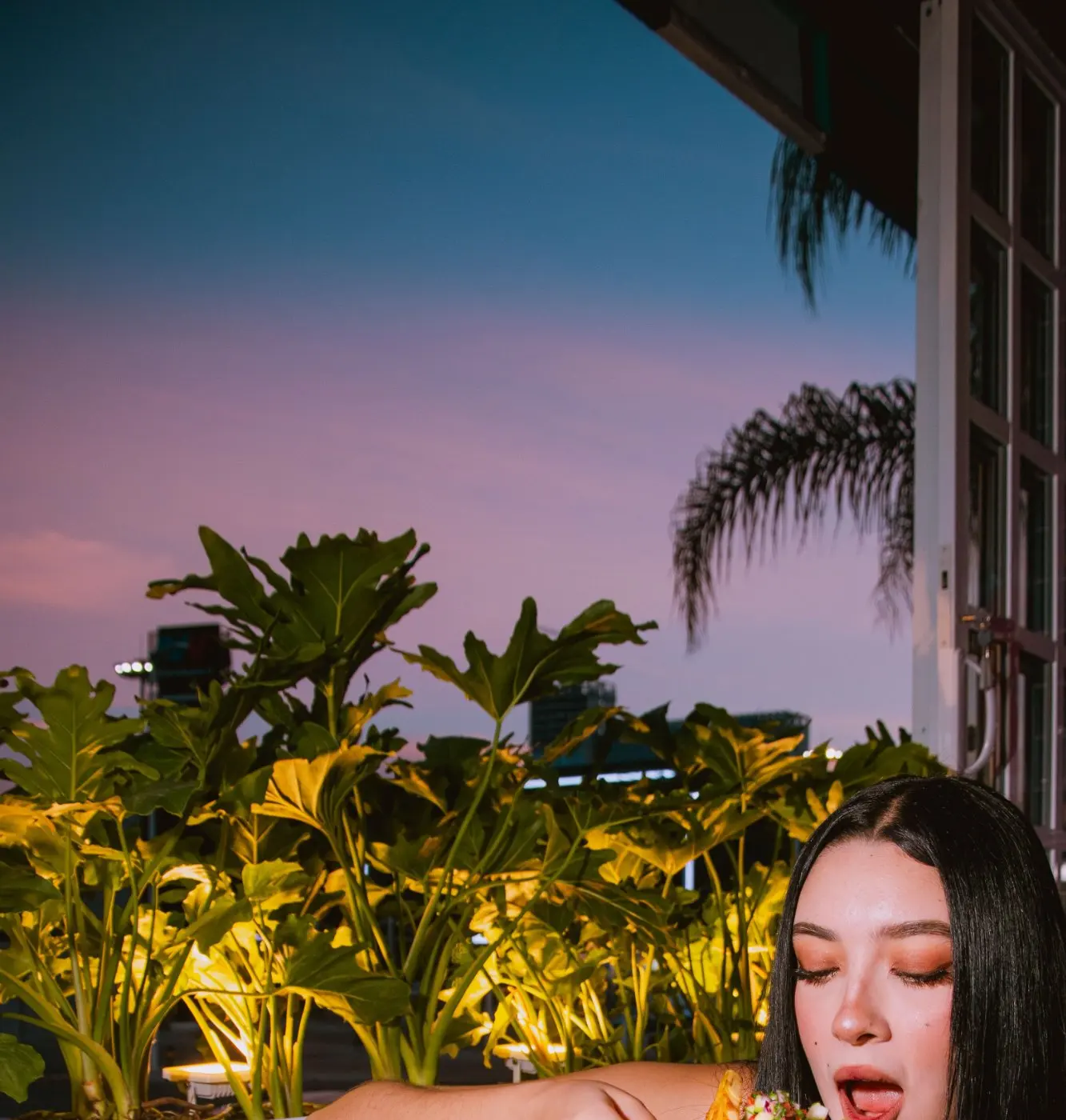 A guest enjoying a dish and a cocktail on the terrace at dusk